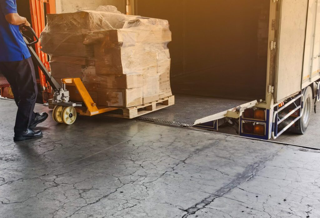 Worker driving forklift loading and unloading shipment carton